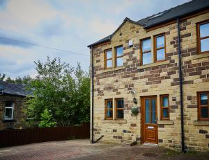 ein Backsteinhaus mit einer roten Tür und einem Zaun in der Unterkunft Listers Lodge in Halifax