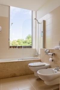 a bathroom with a tub, toilet and sink at Axis Ponte de Lima Golf Resort Hotel in Ponte de Lima