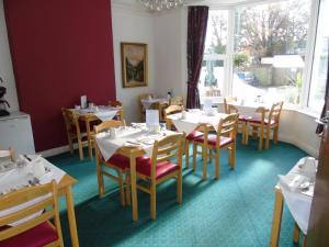 a dining room with tables and chairs and a window at Carrington Guest House in Paignton