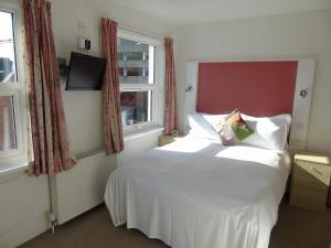 a bedroom with a white bed and a window at Carrington Guest House in Paignton