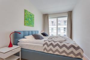 a bedroom with a blue bed and a window at Apartamenty Tulip - visitopl in Międzyzdroje