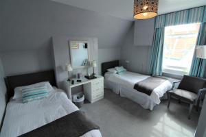 a bedroom with two beds and a mirror and a chair at The Lorna Doone Hotel in Porlock