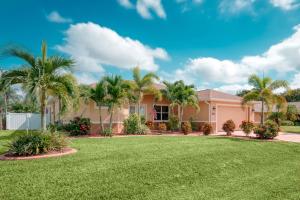 ein Haus mit Palmen und Rasen in der Unterkunft Villa Holiday Sunrise in Cape Coral