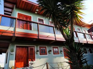 a house with red windows and a palm tree at Pousada Araucária Village in Campos do Jordão