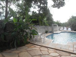 a pool with chairs and a table next to a wall at Pousada Estrela Matutina in Pirenópolis