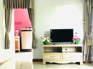 a living room with a tv on a stand with flowers at baan sugaiyah in Phra Ae beach