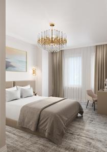 a white bedroom with a large bed and a chandelier at Lumiere Boutique Hotel in Moscow