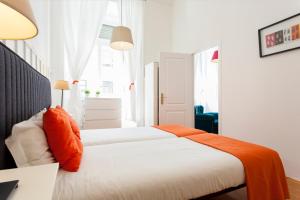 1 Schlafzimmer mit 2 Betten und orangefarbenen Kissen in der Unterkunft Downtown Augusta Apartment in Lissabon