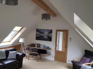 a living room with a black couch and a window at Hawthorn Cottage in Glencoe