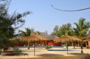 um resort com piscina e guarda-sóis de palha em le baobab de nianing em Nianing