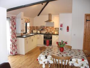 a kitchen with a dining room table with a tablecloth on it at Withersdale Cross Cottages in Mendham