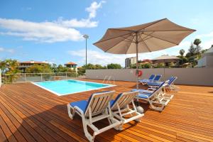 una terraza con sillas, una sombrilla y una piscina en Luxury Villa Nogueira with private pool by HR Madeira en Funchal