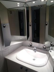 een badkamer met een wastafel en 2 spiegels bij Geräumige zentrumsnahe Altbauwohnung in Wenen