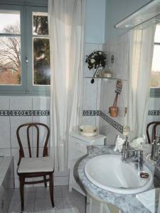 a bathroom with a sink and a chair and a window at Cour Tholmer in Touques
