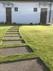 a grassy yard with stepping stones in front of a building at Bagoly in Fertőrákos