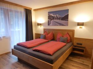ein Schlafzimmer mit einem Bett mit orangefarbener Bettwäsche und einem Fenster in der Unterkunft Haus Alpenflora in Flirsch