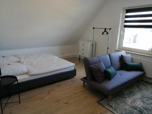 een slaapkamer met een bed, een bank en een raam bij Apartment Central in Ratingen