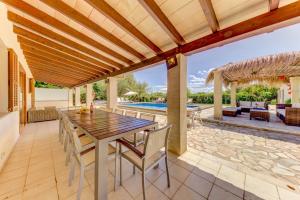a patio with a wooden table and chairs and a pool at Villa Ponent by Sealand Villas in Pollença +27 photos