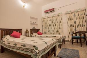 um quarto com 2 camas e uma cadeira azul em Jaipur 1727 Homestay em Jaipur