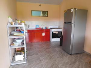 uma cozinha com armários vermelhos e um frigorífico de aço inoxidável em Hostal Casa Las Lajas em Las Lajas