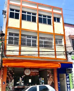 a building with an orange awning and a car parked in front at Hotel Fortaleza III Manaus in Manaus