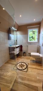 ein Bad mit einem WC, einem Waschbecken und einem Fenster in der Unterkunft Ferienhaus Sanssouci in Stahnsdorf