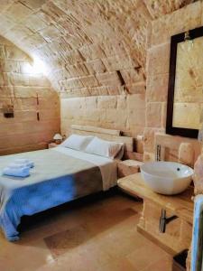 a bedroom with a bed and a sink in a stone wall at Cave Rooms Sassi in Matera