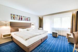 a hotel room with a large bed and a chair at Business Class Hotel Häckermühle in Tiefenbronn