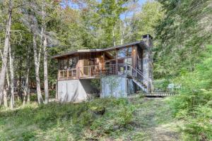 a house in the woods with a wrap around deck at Lily Pond Bungalow in Edgecomb