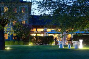 a building with a lawn with two white benches at Hotel Asolo in Asolo