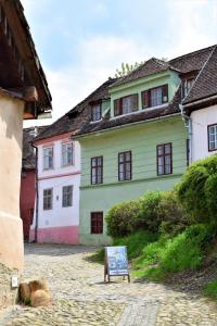 a green building with a sign in front of it at Casa Cojo in Sighişoara