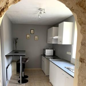 uma cozinha com armários brancos e uma mesa num quarto em cœur de village em La Chapelle-Onzerain