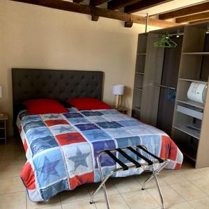 um quarto com uma cama com uma colcha azul e vermelha em cœur de village em La Chapelle-Onzerain