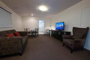 a living room with a couch and a television and a table at The Towers on the Park in Christchurch