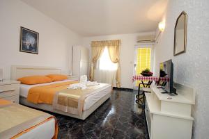 Cette chambre comprend deux lits et une télévision. dans l'établissement Apartments Kruna Jovanović, à Sutomore