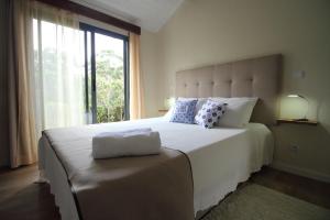 a bedroom with a large white bed with a window at Cantinho da Luz in Ponta Delgada