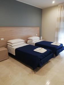 two beds in a room with blue sheets at Casa Bandiera in Siracusa