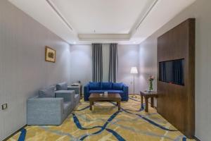 een woonkamer met een blauwe bank en een tv bij Sansa Hotel in Jeddah