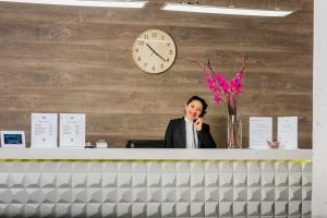 a woman talking on a phone at a desk with a clock at Hotel Viza in Arequipa