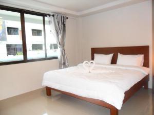 a bedroom with a bed with white sheets and a window at The City House in Krabi