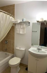 a white bathroom with a toilet and a sink at Village Inn & Suites - Sudbury in Lively