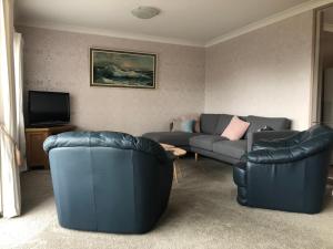 een woonkamer met 2 banken en een tv bij Central Howick Uxbridge Apartments in Auckland