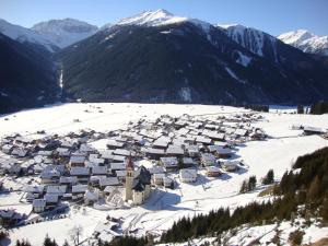 a village in the snow with mountains in the background at Gästehaus Obererlacher in Obertilliach