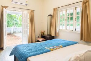 a bedroom with a bed with a blue blanket on it at Casa Arvana Near Calangute Beach in Calangute
