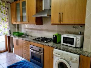 a kitchen with a stove top oven next to a microwave at Casa Avó Rosa in Nazaré