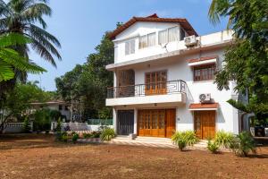 a white house with wooden doors and a yard at Casa Arvana Near Calangute Beach in Calangute