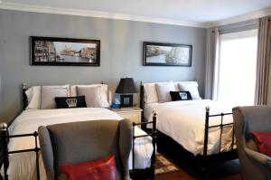 two beds in a room with two chairs at Casa Blanca Boutique Bed & Breakfast in Niagara on the Lake