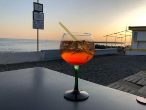 La Casa di Dory في جينوا: وجود كأس من النبيذ على طاولة بالقرب من الشاطئ