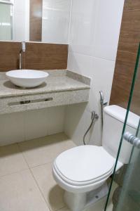 a bathroom with a white toilet and a sink at Hotel Amendoeiras in Prado