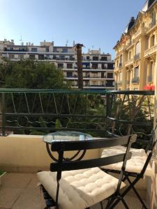 uma mesa de vidro e cadeira numa varanda com edifícios em chez Eva em Nice